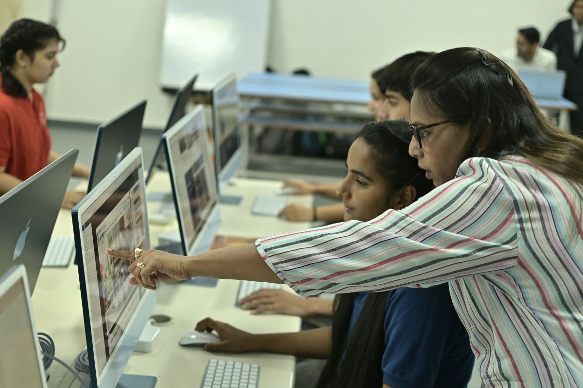 A teacher guiding students through a computer lab session
