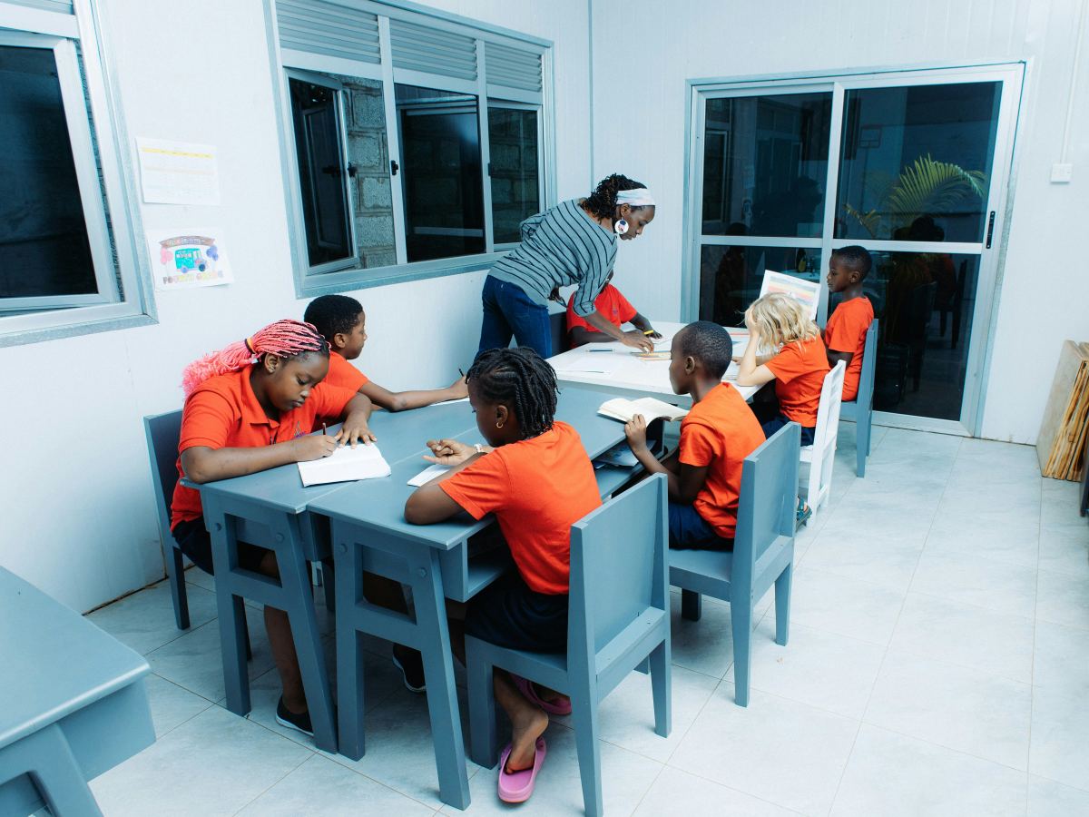 A teacher helping pupils at their desks in a Kenyan classroom